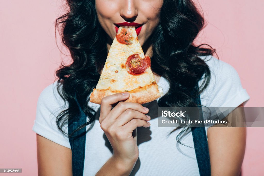 cortada a foto da mulher comer pizza no fundo rosa - Foto de stock de Pizza royalty-free