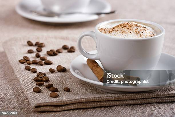 A Cup Full Of Cappuccino Surrounded By Coffee Beans Stock Photo - Download Image Now