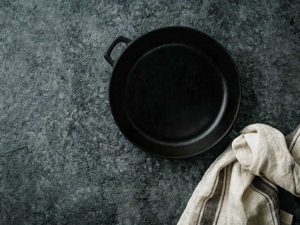 istock blank cast iron frying pan on dark grey concrete background, top view, blank space for text 942930540
