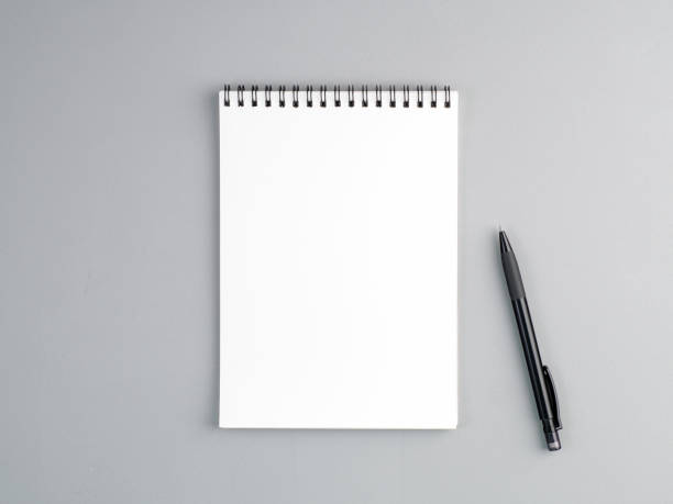 foglio bianco del blocco appunti con spirale e penna su uno sfondo strutturato grigio neutro - note pad foto e immagini stock