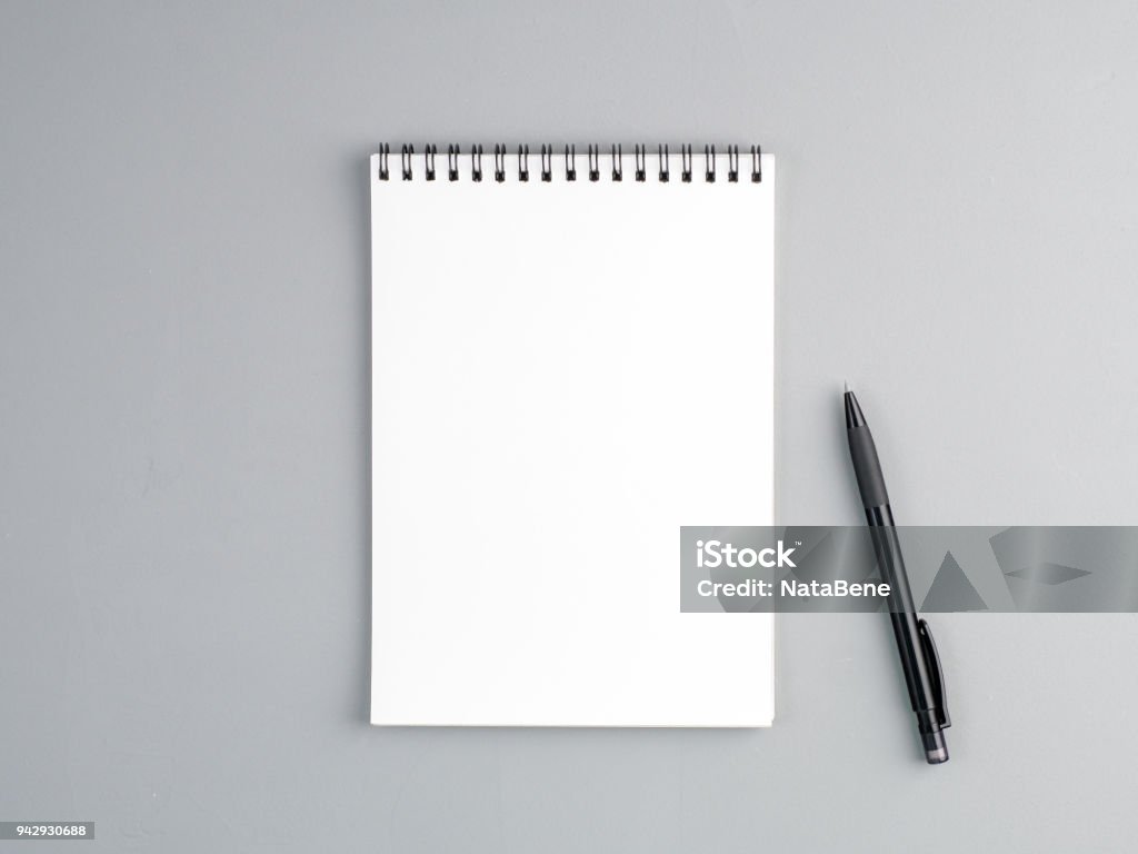 blank sheet of notebook with a spiral and pen on a neutral gray textured  background Note Pad Stock Photo