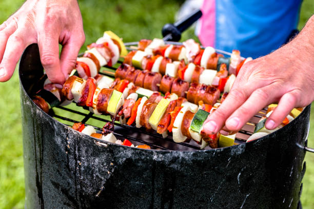 grillen von lebensmitteln auf grill, hände vorbereitung spieße mit gemüse und wurst, bbq auf dem rasen, draußen sommer party-konzept - barbecue grill broiling barbecue vegetable stock-fotos und bilder