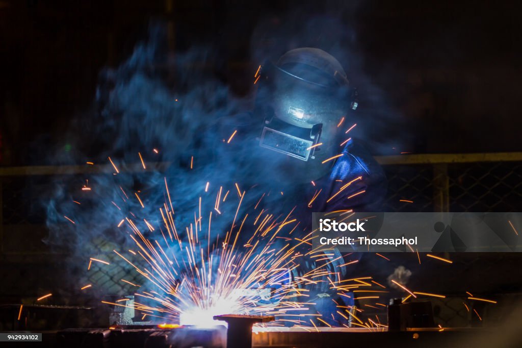 Worker is welding automotive part in car factory Welder Stock Photo
