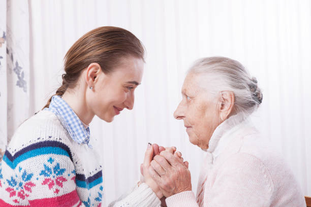 istock Senior and caregiver holding hands at home 942934844