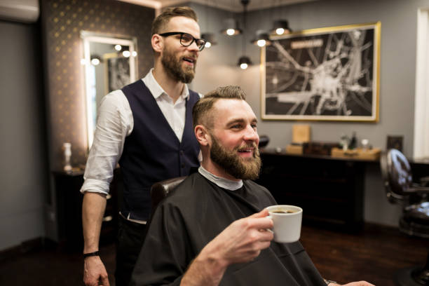 istock Happy barber and customer drinking coffee in salon 942941914