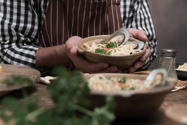 istock Handsome bearded cheef cook prepairing spaghetti on a kitchen, Chef cooks meal 942942322