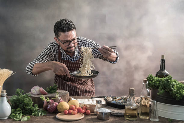 istock Handsome bearded cheef cook prepairing spaghetti on a kitchen, Chef cooks meal 942948922