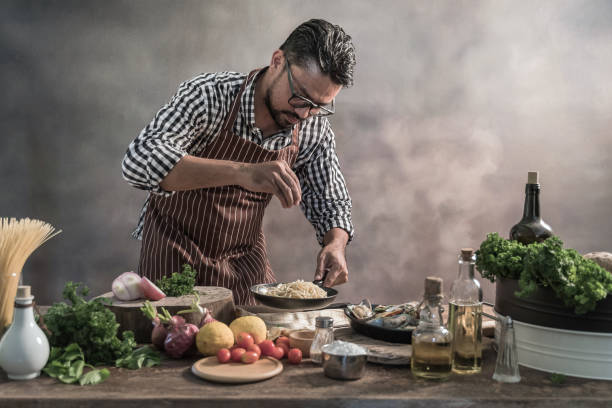 Handsome bearded cheef cook prepairing spaghetti on a kitchen, Chef cooks meal
