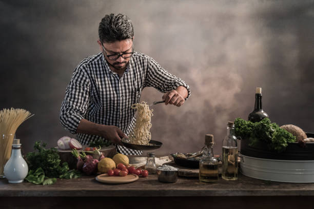 istock Handsome bearded cheef cook prepairing spaghetti on a kitchen, Chef cooks meal 942949240