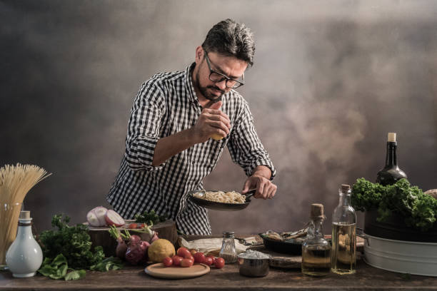 istock Handsome bearded cheef cook prepairing spaghetti on a kitchen, Chef cooks meal 942949408