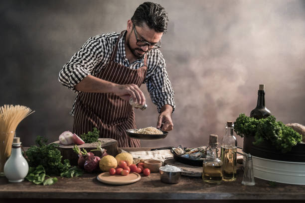 istock Handsome bearded cheef cook prepairing spaghetti on a kitchen, Chef cooks meal 942949482