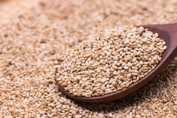 istock white sesame in wooden spoon on sesame background. 942958748