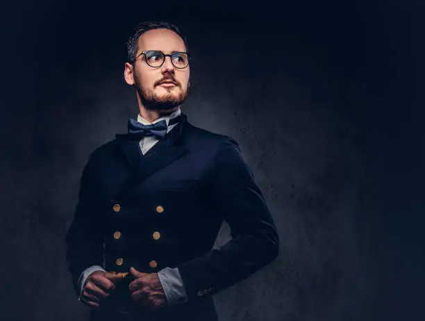 Photo of Portrait of a bearded male in glasses and antique suit on a dark