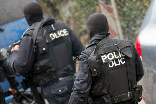 Special law enforcement unit. Special police force units in uniforms, bulletproof vests, firearms and guns. Masked police officers. Special Assault Team during mission. From their backs.