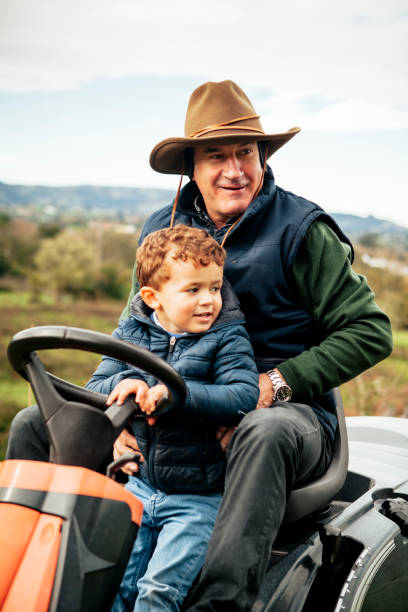 istock Grandfather with grandson on ride-on lawn mower 942976220