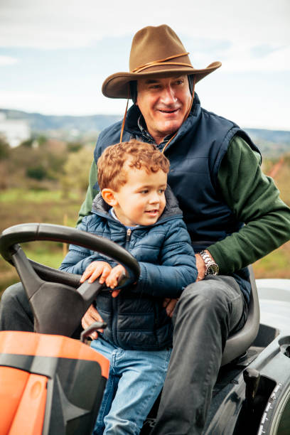 istock Grandfather with grandson on ride-on lawn mower 942976314