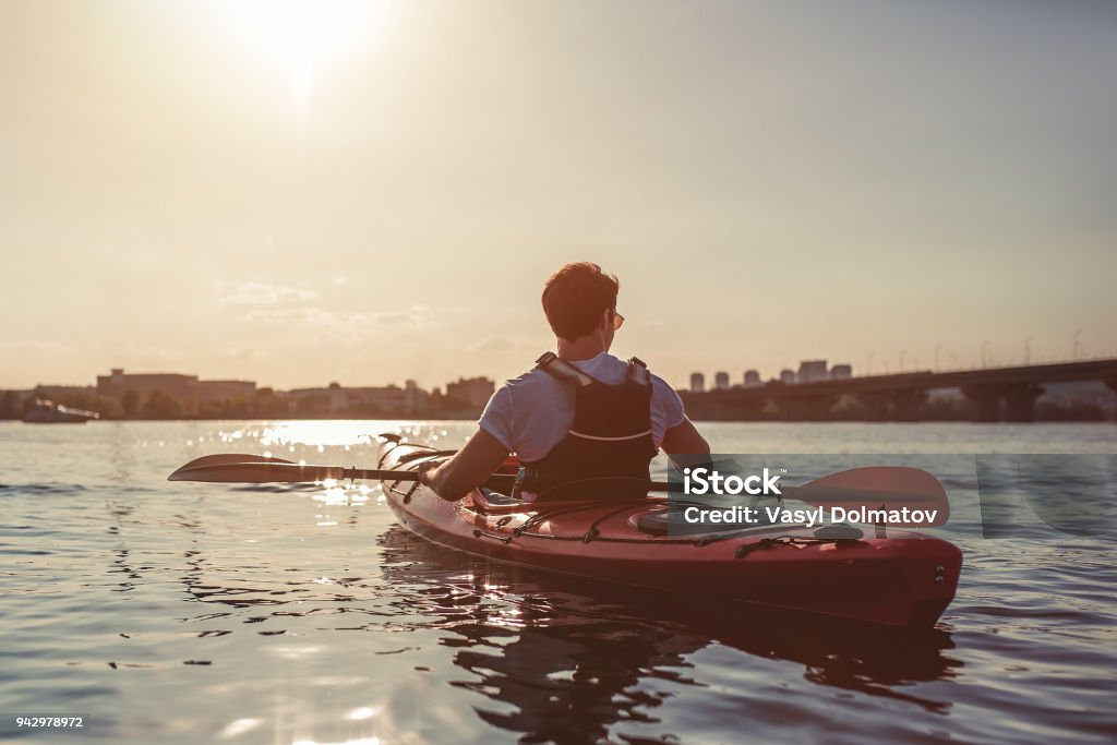 Man kayaking on sunset Handsome sporty man is kayaking on sunset. Canoeing alone. Kayaking Stock Photo