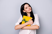 Pretty smiling happy lady hugging present of her dreams against gray background