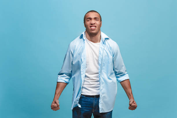 istock The young emotional angry man screaming on blue studio background 942988486