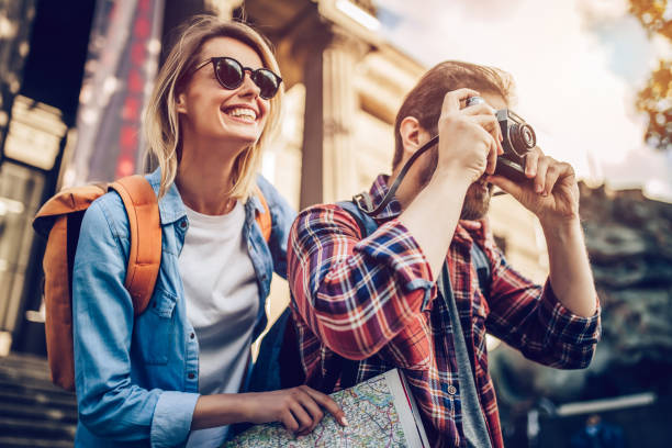 Couple of tourists Couple of tourists is exploring new city together. Smiling and making photo on a retro camera. vacations photos stock pictures, royalty-free photos & images