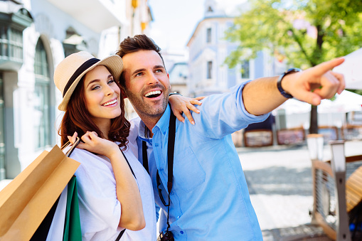 Couple of happy tourists doing shopping in old town