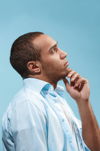 istock Thoughtful Afro-American man is looking thoughtfully against blue background 943007696