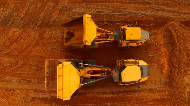 Aerial photo of a pair of dump trucks parked and with their beds raised after a day's work. Photo was taken with a DJI Inspire 1