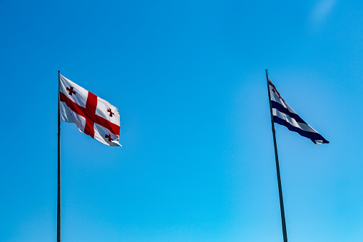 National flags of Georgia and Adjara against a blue sky on a sunny day