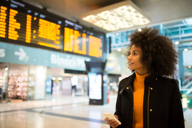 souriant femme afro-américaine. - arrival airport arrival departure board sign photos et images de collection
