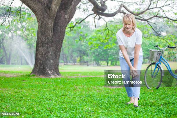 Senior Woman Walking In Autumn Park And Having Knee Pain Arthritis Pain Concept Stock Photo - Download Image Now