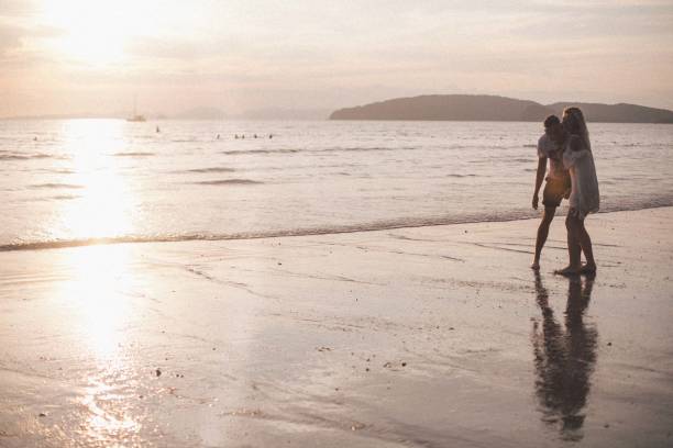 istock Couple having fun in the sea at sunset beach 943029786