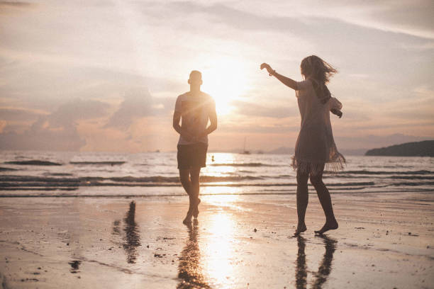 istock Couple having fun in the sea at sunset beach 943029802