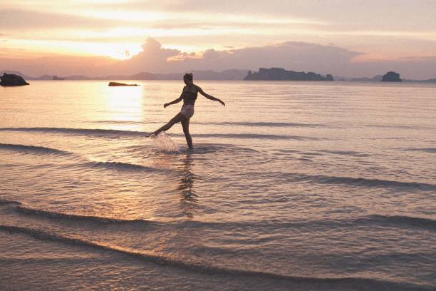 istock Barefoot woman running towards sea during sunset 943029976