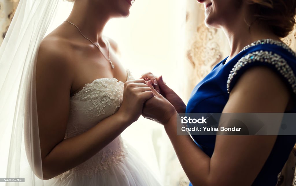 Bride on wedding day holding her mother's hands. Concept of relationship between moms and daughters Bride Stock Photo