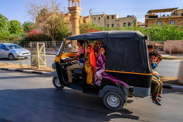 Group of happy Gypsy Indian children riding tuk-tuk (moto rickshaw), Rajasthan, India.
