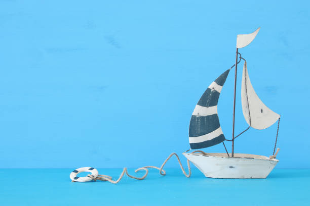 istock nautical concept with white decorative sail boat over blue wooden table and background. 943041442
