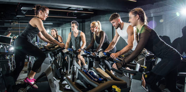 groupe de personnes sportive sur le cyclisme de classe - spinning instructor exercising gym photos et images de collection