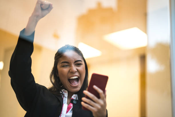 donna d'affari asiatica che festeggia con il cellulare - businesswoman business cheering women foto e immagini stock