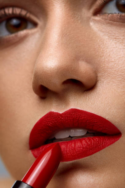istock Makeup And Cosmetics. Woman Face With Red Lips Putting Lipstick 943046626