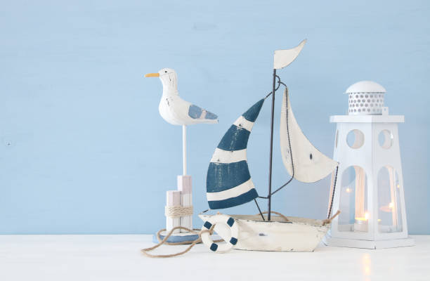 istock nautical concept image with white decorative seagull bird, boat and lighthouse lantern over light blue background. 943050782