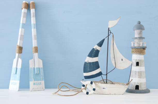 istock nautical concept image with decorative oars, boat and lighthouse over light blue background. 943050802