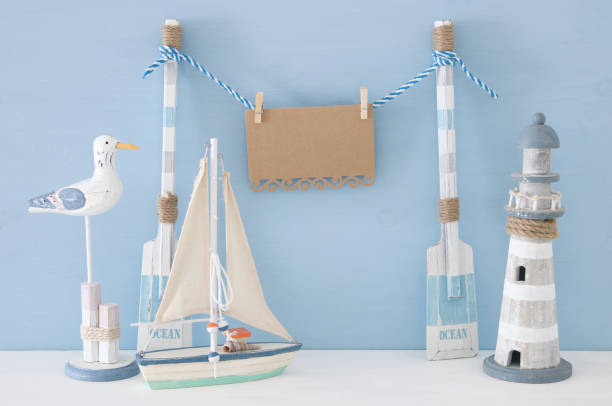 istock nautical concept with wooden decorative boat oars and empty hanging note on a string next to lighthouse, seagull and boat over blue background. 943050856