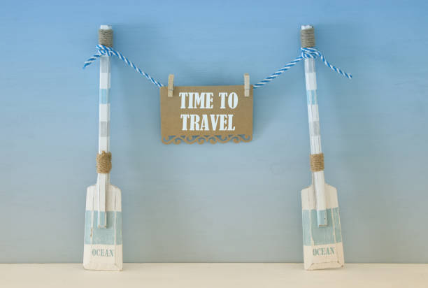 istock nautical concept with wooden decorative boat oars and note hanging on a string over blue background. 943050906