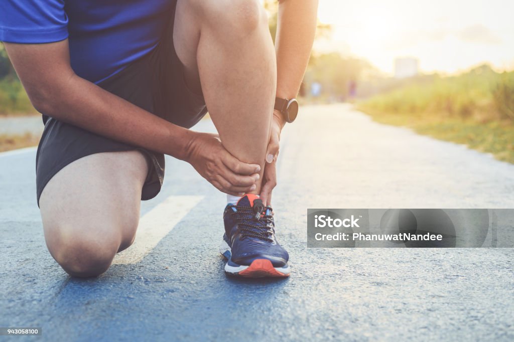 Injury from workout concept : Asian man use hands hold on his ankle while running on road in the park. Focus on ankle. Injury from workout concept : The asian man use hands hold on his ankle while running on road in the park. Focus on ankle. Ankle Stock Photo