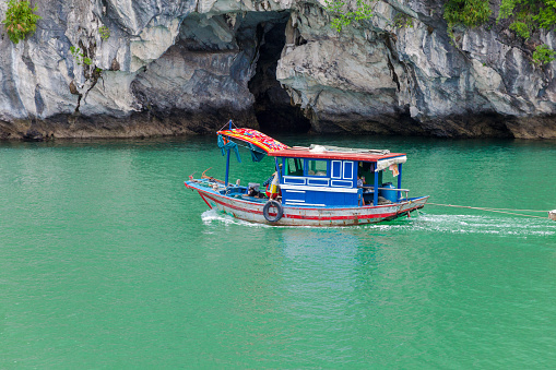 Halong Bay, Vietnam - : Vietnamese people working on their fishing boat on Halong Bay. This is a typical family and the parents are at the front of the boat to fish and their boy is in the back. The child is tied not to fall in water..On the boat, fishing net, and clothesline.
