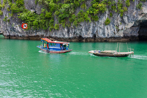 Halong Bay, Vietnam 18/8.2014 : Vietnamese people working on their fishing boat on Halong Bay. This is a typical family and the parents are at the front of the boat to fish and their boy is in the back. The child is tied not to fall in water..On the boat, fishing net, and clothesline.