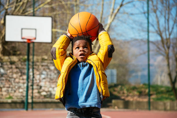 The basket is too high for little boys Cute little boy holding a basket ball trying make a score kids winter coat stock pictures, royalty-free photos & images