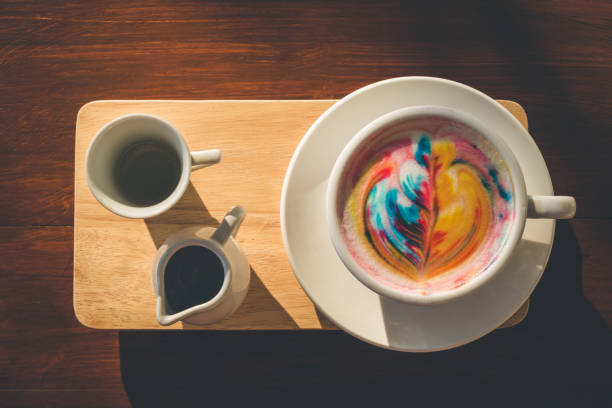 Colorful rainbow latte coffee in white cup on wooden table with copy space for text or design
