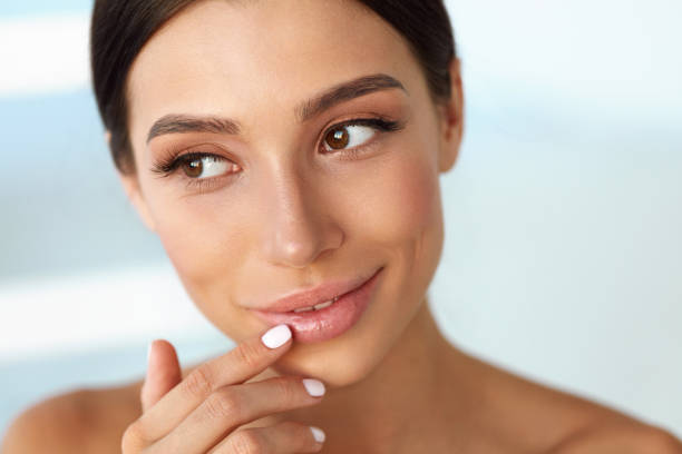 istock Beauty Face. Beautiful Woman Touching Lips With Lip Balm On 943061900