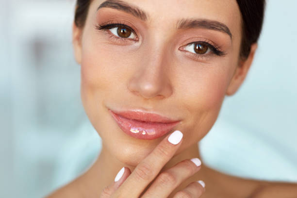 istock Beauty Face. Beautiful Woman Touching Lips With Lip Balm On 943062104